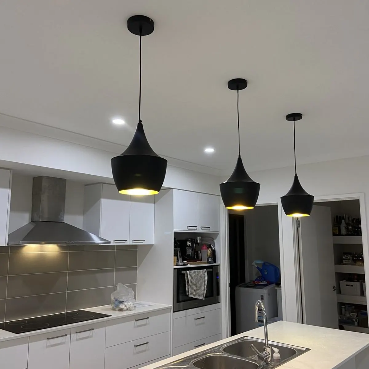 Three black pendant lights hanging over a kitchen island bench