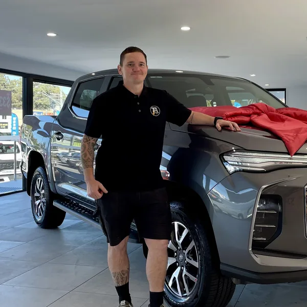 Tom Ashcroft standing beside the TA Electrical GC ute, in a TA Electrical polo